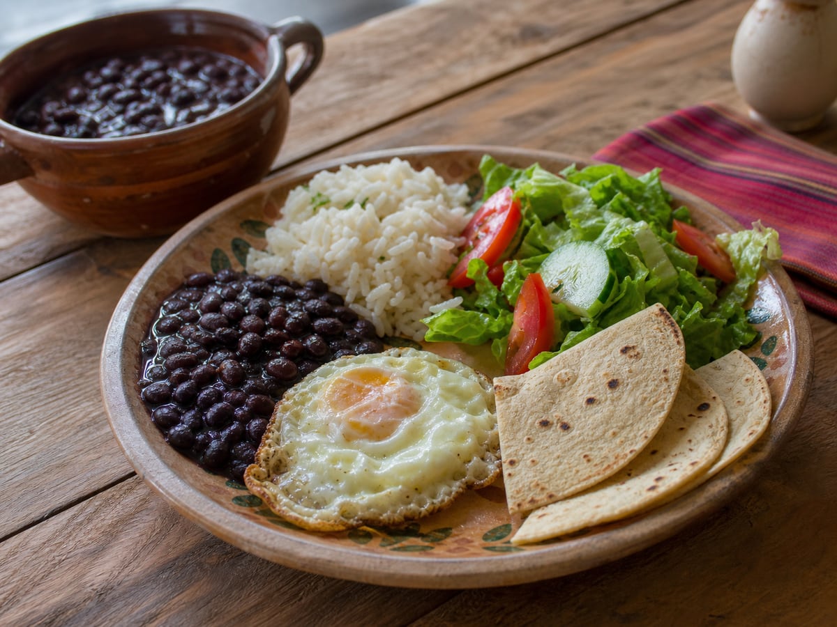 Frijoles con arroz, huevo y ensalada servido en una porción casera con ingredientes visibles