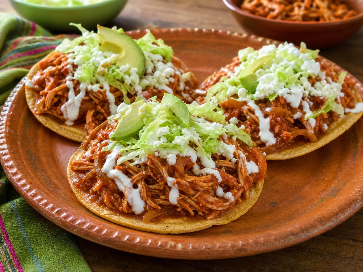 Tostadas mexicanas con tinga de pollo, crema, queso fresco, lechuga y aguacate